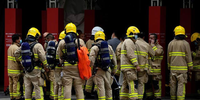 Firefighters stand outside the World Trade Centre in Hong Kong's popular Causeway Bay shopping district on Wednesday, Dec. 15, 2021.