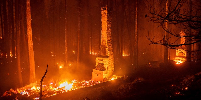 Seen in a long camera exposure, chimneys stand at residences leveled by the Caldor Fire along Highway 50 on Aug. 29, 2021, in Eldorado National Forest, California.