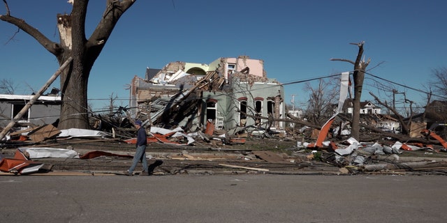 A man walks by a house destroyed by tornadoes in Mayfield, Kentucky.