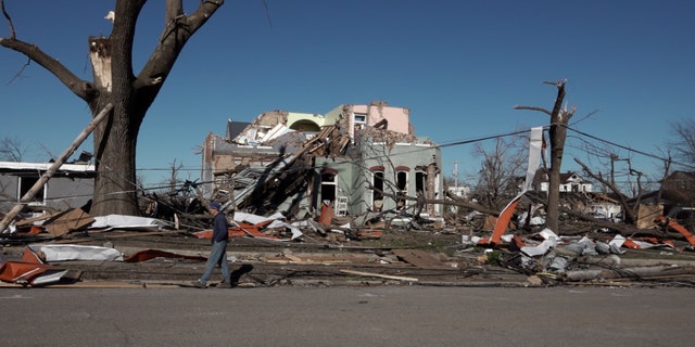 A man walks by a house destroyed by tornadoes in Mayfield, Kentucky.