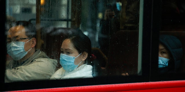 Passengers wearing face masks ride a bus through Westminster in London, Monday, Dec. 27, 2021. 