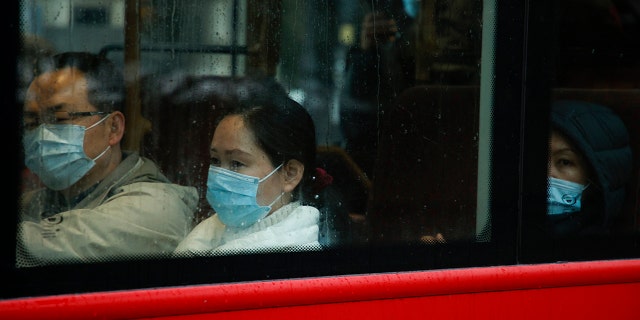 Passengers wearing face masks ride a bus through Westminster in London, Monday, Dec. 27, 2021.