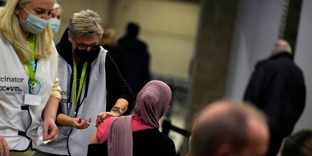 A vaccinator administers a Moderna booster vaccine to a woman at the Antwerp Expo vaccine center in Antwerp, Belgium, on Monday, Dec. 27, 2021. 