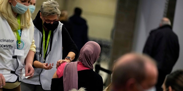A vaccinator administers a Moderna booster vaccine to a woman at the Antwerp Expo vaccine center in Antwerp, Belgium, on Monday, Dec. 27, 2021.