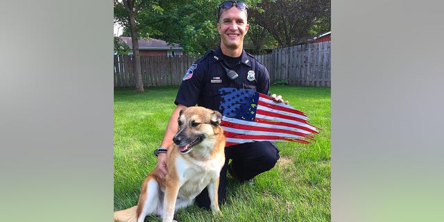 A police officer and his dog are shown here with a unique flag creation from the Henderson father-son team.