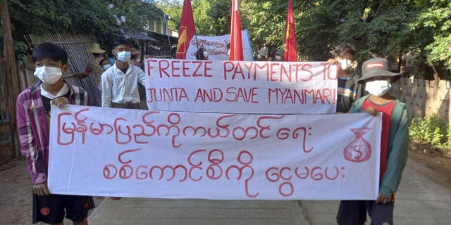 Protesters  in the village of Latpantaung, Burma, holding signs calling for the freezing of revenues the military gets from the sale of oil and gason Oct. 28, 2021.