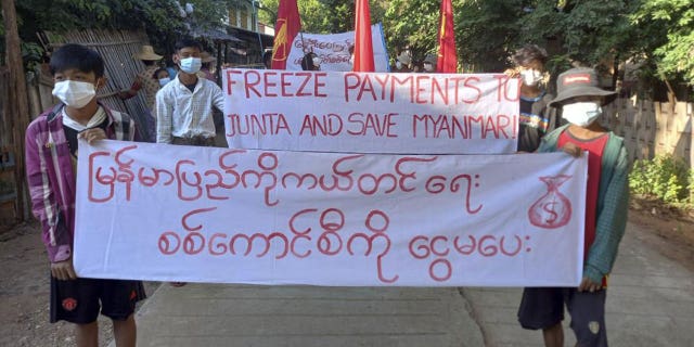 Protesters in the village of Latpantaung, Myanmar, hold signs calling for the freezing of revenues the military gets from the sale of oil and gason Oct. 28, 2021.