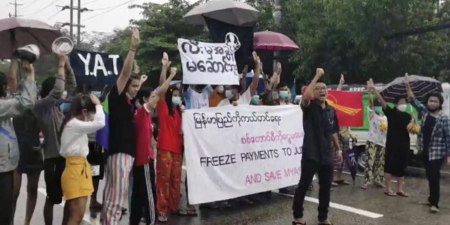 Protesters hold signs in Yangon on Oct. 30, 2021, calling for the freezing of revenues from oil and gas sales in Myanmar.
