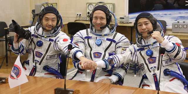 Alexander Misurkin, center, Yusaku Maezawa, right, and Yozo Hirano pose prior to the launch Wednesday, Dec. 8, 2021. 