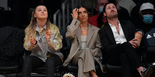 JoJo Siwa (L), Jenna Johnson Chmerkovskiy (C) and her husband Valentin Chmerkovskiy attend the game between the Los Angeles Lakers and Orlando Magic at Staples Center on December 12, 2021 in Los Angeles, California. 