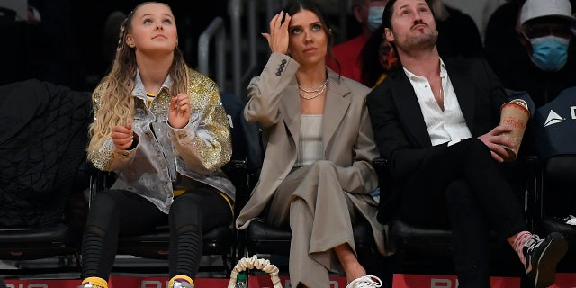 JoJo Siwa (L), Jenna Johnson Chmerkovskiy (C) and her husband Valentin Chmerkovskiy attend the game between the Los Angeles Lakers and Orlando Magic at Staples Center on December 12, 2021 in Los Angeles, California.