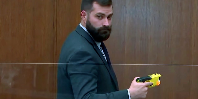 Sam McGinnis holds the Taser of former police officer Kim Potter on Dec. 13, 2021, as he testifies in her trial in Minneapolis.