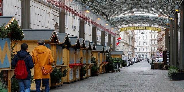 Two people walk by closed Christmas markets and shops due to the lockdown in Vienna, Austria, Tuesday, Nov. 30, 2021. 