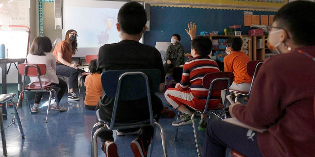 A teacher gives a lesson to masked students in their classroom on September 27, 2021 in New York City.