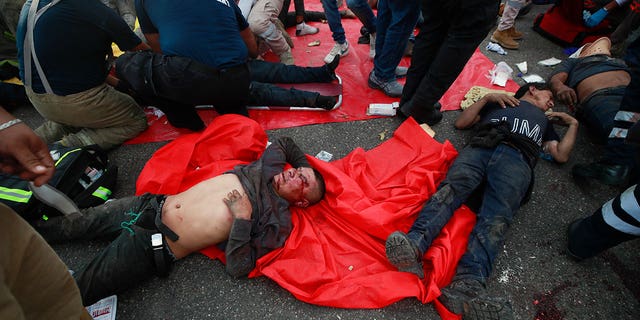 Injured migrants are cared for on the side of the road next to the overturned truck on which they were traveling near Tuxtla Gutierrez, Chiapas state, Mexico, Thursday, Dec. 9, 2021.