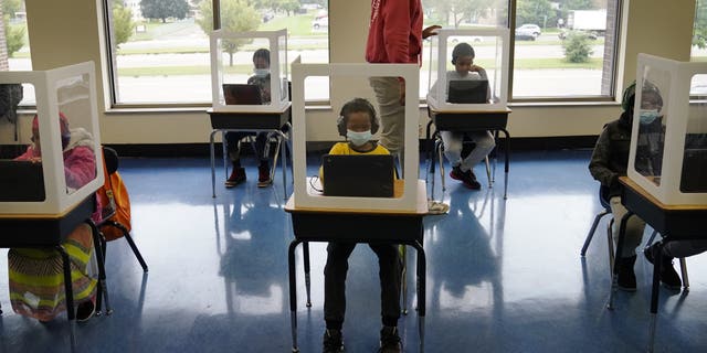 MINNEAPOLIS, MN,- SEPTEMBER 8 - It was back to school for some students at Harvest Best Academy Tuesday in Minneapolis, but with masks, plastic barriers and other new precautions in the era of COVID-19. Here, para professional Jaevon Walton, middle, reminded a student to wear his face mask in a learning pod of 2nd through 7th graders, Tuesday, Sept. 8, 2020, in Minneapolis.