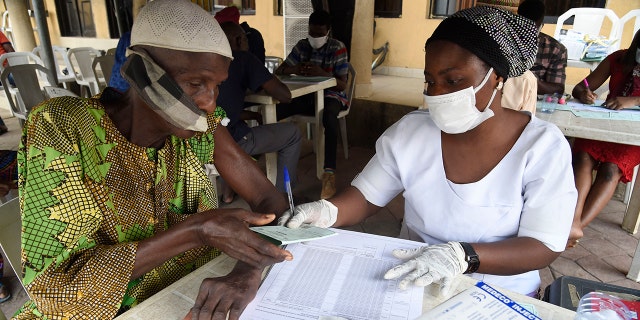 A man receives a vaccine card from a health official after being administered a dose of Astrazeneca's Vaxzevria COVID-19 vaccine Nov. 26, 2021, at Secretariat Community Central Mosque, Alausa, Ikeja, in Lagos.