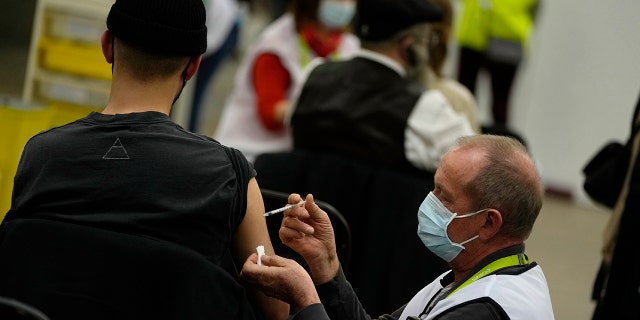 A vaccinator administers a Moderna booster vaccine to a man at the Antwerp Expo vaccine center in Antwerp, Belgium, on Monday, Dec. 27, 2021.