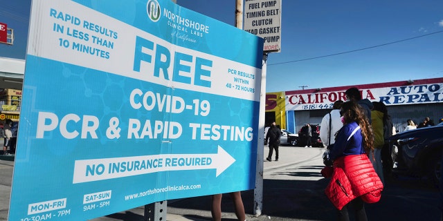 People line up for a free COVID-19 rapid test at a gas station in the Reseda section of Los Angeles on Sunday, Dec. 26, 2021, as California braces for a post-holiday virus surge.