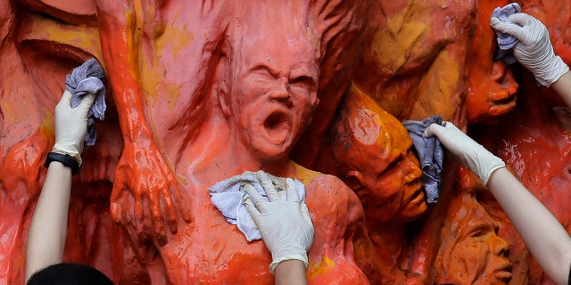 University students clean the "Pillar of Shame" statue, a memorial for those killed in the 1989 Tiananmen crackdown, at the University of Hong Kong Tuesday, June 4, 2019. A monument at a Hong Kong university that commemorated the 1989 Tiananmen massacre was boarded up by workers late Wednesday, Dec. 22, 2021, prompting fears over the future of the monument as the city's authorities crack down on dissent.