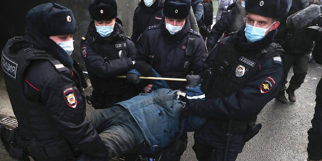 Police officers detain a demonstrator as people gather in front of the Supreme Court of the Russian Federation, in Moscow, Russia, Tuesday, Dec. 28, 2021.