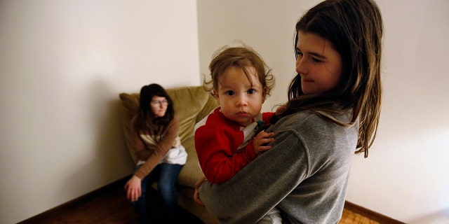 Abby Olmstead, age 10, holds her 1-year-old brother, Liam Myers, while her 13-year-old sister Makayla Olmstead sits on the couch, on Thursday, Dec. 2, 2021, at their home in Paw Paw, Michigan. Abby has been working with support staff at her school to manage her emotions in the classroom at Paw Paw Elementary School. She said she sometimes feels anxious and blurts out things in class. Mindfulness exercises help calm and distract her, she said. She said the behavior specialist at her school "always makes me laugh when I have anxiety, and that's not a bad thing."