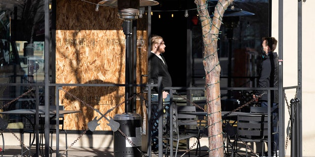 Dec. 28: Workers confer close to a sheet of plywood covering a window of a pizza parlor in Lakewood, Colo., near one of the scenes of a shooting spree that left five people dead—including the suspected shooter Monday evening—and left three more people wounded. (AP Photo/David Zalubowski)