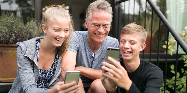 Duelmen, Germany - August 10: Two teenagers and their father are busy with their smartphones. Staged picture on August 10, 2017 in Duelmen, Germany. (Photo by Ute Grabowsky/Photothek via Getty Images)