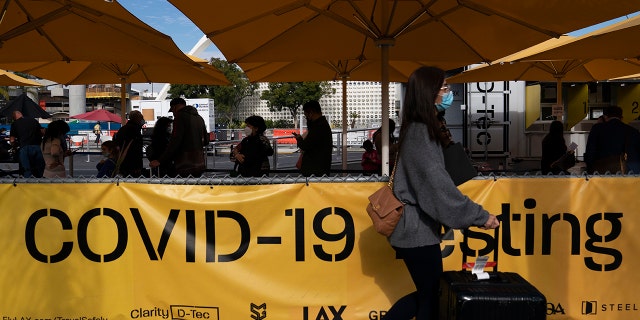 Travelers wait in line to get tested for COVID-19 at Los Angeles International Airport, Monday, Dec. 20, 2021.