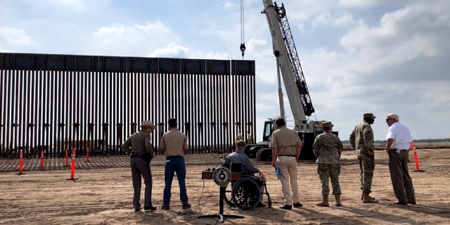 Texas Gov. Greg Abbott, Land Commissioner George P. Bush, and Texas Facilities Commissioner Steven Alvis watch a section of the border wall go up following Saturday's press conference. 