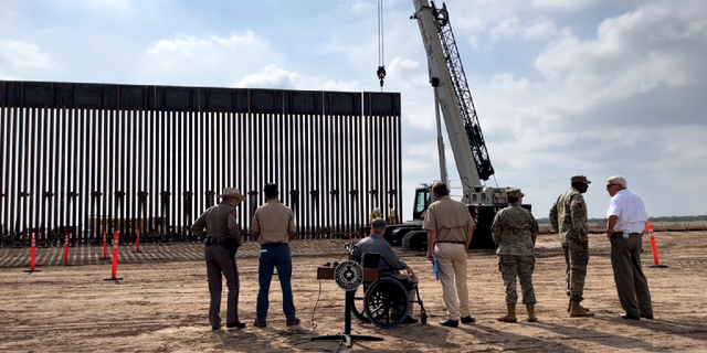 Texas Gov. Greg Abbott, Land Commissioner George P. Bush, and Texas Facilities Commissioner Steven Alvis watch a section of the border wall go up following Saturday's press conference.