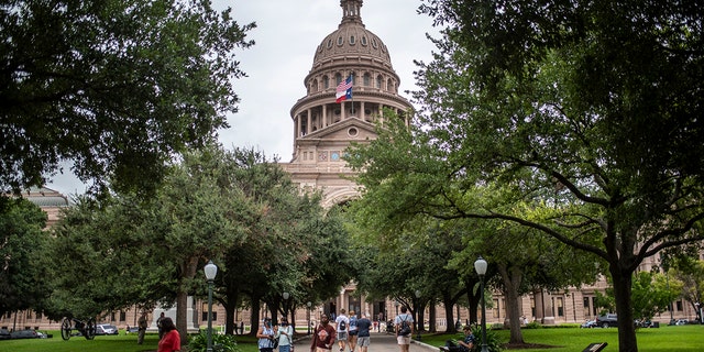 Visitors walk around outside the Texas State Capitol building on July 12, 2021, in Austin, Texas.