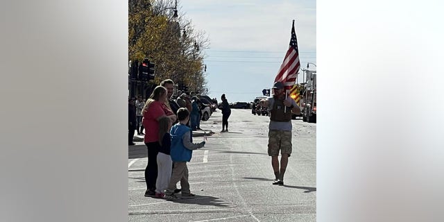Derek Redenius, The Walking Patriot, walks by a waving crowd. (Derek Redenius)