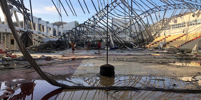 Residents walk inside a damaged sports complex building on Monday Dec. 20, 2021, that was used as an evacuation center when its roof collapsed due to Typhoon Rai at Siargao island in Surigao del Norte province, southern Philippines. 