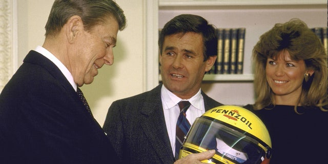 President Ronald Reagan gets a helmet from race car driver Al Unser.