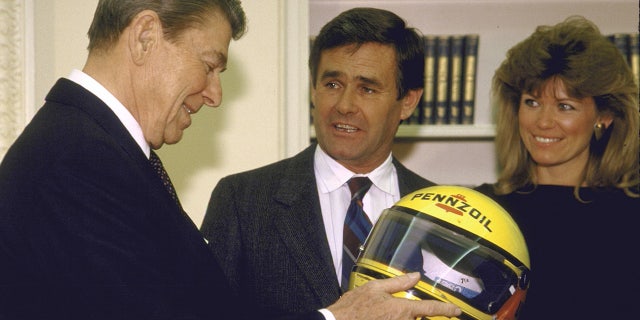 President Ronald Reagan gets a helmet from race car driver Al Unser.