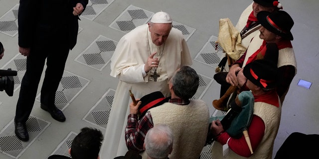 Pope Francis speaks to bagpipe players at the end of his weekly general audience in the Paul VI Hall, at the Vatican, Wednesday, Dec. 22, 2021.
