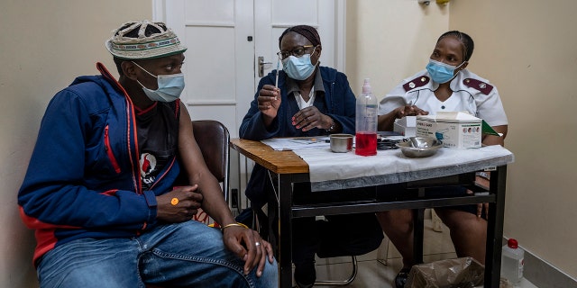Medical staff talk to a man about to be vaccinated against COVID-19 at the Hillbrow Clinic in Johannesburg, South Africa, Monday Dec. 6, 2021.