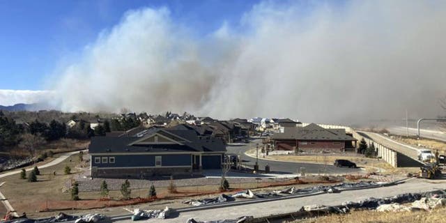 Smoke from a wildfire rises in the background, Thursday, Dec. 30, 2021, in Superior, Colo. (AP Photo/David Zelio)