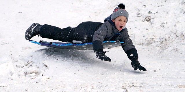 Titus Gonzalez goes airborne after hitting a bump while sledding where nearly a foot of snow fell over the weekend, Monday, Dec. 27, 2021, in a city park in Bellingham, Washington.