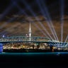 The Waka Hourua sails underneath a light show from the Skytower and harbour bridge during Auckland New Year's Eve celebrations on January 01, 2022 in Auckland, New Zealand.