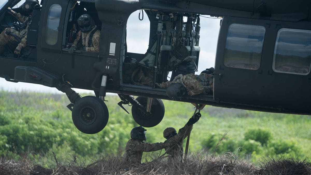 Engineers hook a bundle of Christmas trees to a helicopter, a similar technique they'd use to haul emergency supplies. 