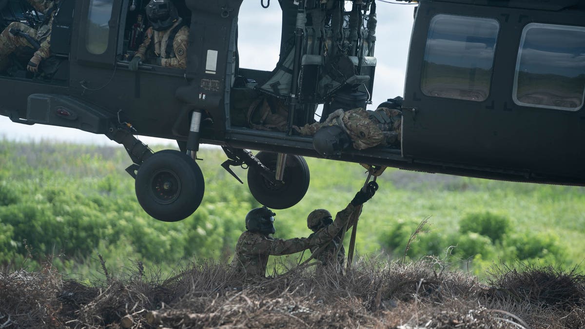 Engineers hook a bundle of Christmas trees to a helicopter, a similar technique they'd use to haul emergency supplies. 