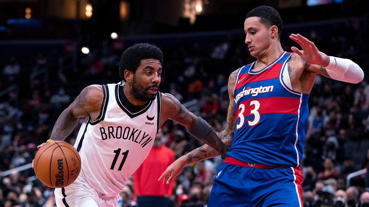 Brooklyn Nets guard Kyrie Irving (11) drives to the basket against Washington Wizards forward Kyle Kuzma (33) during the first half of an NBA basketball game Wednesday, Jan. 19, 2022, in Washington.