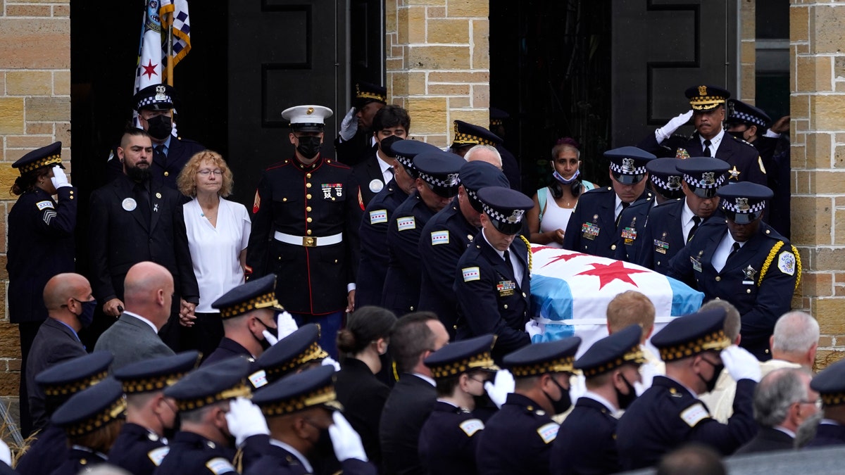 Elizabeth French, in white, and her son Andrew, left, follow the casket of her daughter, Chicago police officer Ella French, after a funeral service at the St. Rita of Cascia Shrine Chapel Thursday, Aug. 19, 2021, in Chicago.