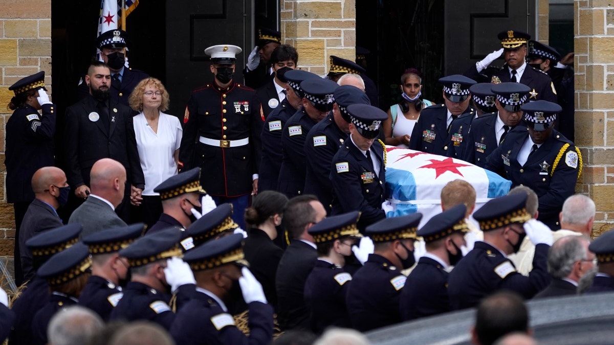 Elizabeth French, in white, and her son Andrew, left, follow the casket of her daughter, Chicago police officer Ella French, after a funeral service at the St. Rita of Cascia Shrine Chapel Thursday, Aug. 19, 2021, in Chicago.