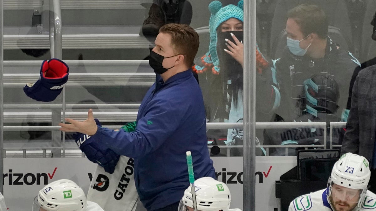 Seattle Kraken fan Nadia Popovici, center, reacts after she was introduced along with Vancouver Canucks assistant equipment manager Brian "Red" Hamilton, standing, during the first period of an NHL hockey game Saturday, Jan. 1, 2022, in Seattle. 