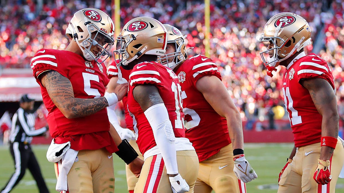 San Francisco 49ers quarterback Trey Lance, left, celebrates after throwing a touchdown pass to Deebo Samuel, middle, during the second half of an NFL football game against the Houston Texans in Santa Clara, Calif., Sunday, Jan. 2, 2022.