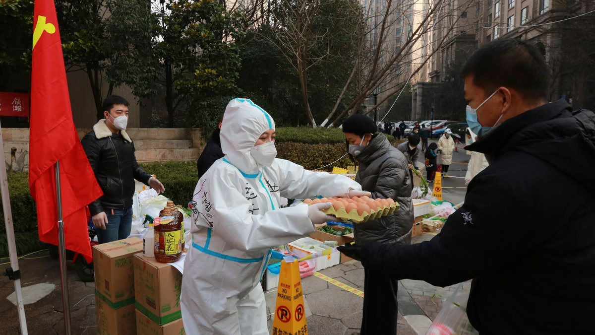 A community volunteer hands over eggs to a buyer at a temporary food store to provide supplies to residents outside a residential block in Xi'an city in northwest China's Shaanxi province Monday, Jan. 03, 2022. (Chinatopix Via AP)
