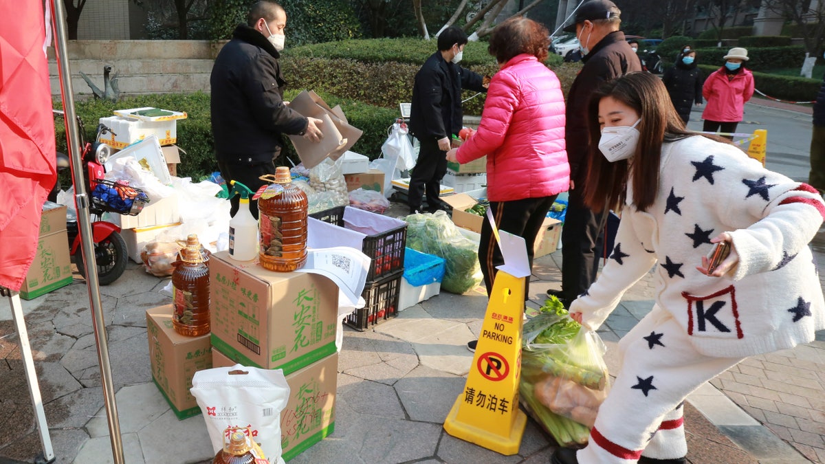 Residents shop for food at a temporary food store set up to serve residents outside a residential block after the suspension of delivery services in Xi'an city in northwest China's Shaanxi province Monday, Jan. 3, 2022.(Chinatopix Via AP)